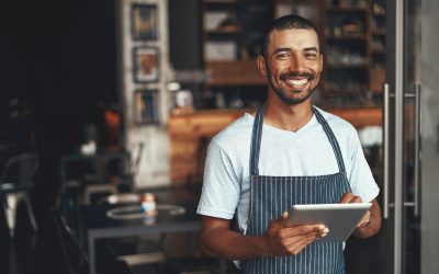 Smiling male owner standing at the doorway of his cafe
